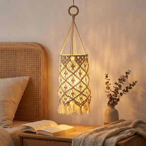 Abat-jour macramé beige à pompons au-dessus d'une table de chevet dans une chambre cosy