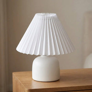 Abat-jour plissé conique en tissu blanc sur une lampe allumée