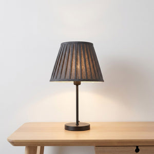 Abat-jour plissé en tissu gris sur lampe de bureau dans un espace de travail épuré