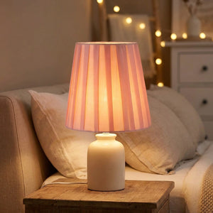 Abat-jour plissé en tissu rose sur lampe de table dans une chambre chaleureuse