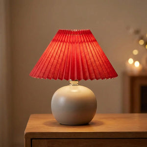 Abat-jour plissé conique en tissu coloris Rouge sur une lampe allumée