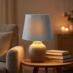 Abat-jour en velours gris sur une lampe en céramique près d un fauteuil de lecture