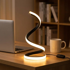 Lampe de bureau LED en spirale allumée à côté d'un ordinateur portable et d'une tasse