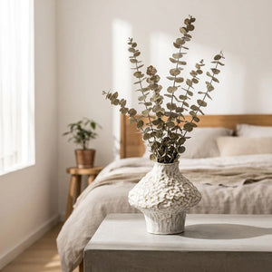 Vase céramique wabi sabi blanc avec eucalyptus dans une chambre moderne