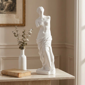Sculpture Vénus de Milo posée sur une console en marbre blanc avec vase et branche d'eucalyptus