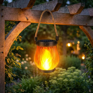 Lanterne solaire à effet flamme suspendue à une pergola en bois dans un jardin au crépuscule