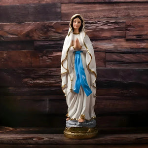 Photo AliExpress statue Vierge Marie en résine peinte robe blanche écharpe bleue socle doré vue de face sur fond bois