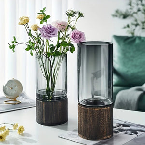 Deux vases cylindriques en verre fumé avec fleurs violettes sur table blanche