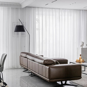 Voilage blanc en tulle transparent le long d'une grande baie vitrée de salon