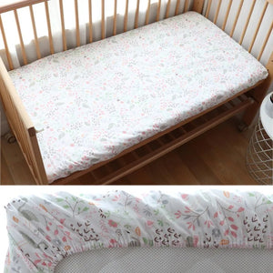 Vue rapprochée du drap housse bébé motif cygne rose et fleurs sur un matelas de berceau