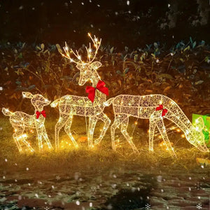 Rennes lumineux de Noël en métal LED dans un jardin enneigé la nuit