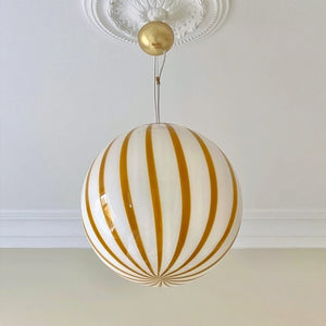Suspension boule en verre rayée jaune vue de près