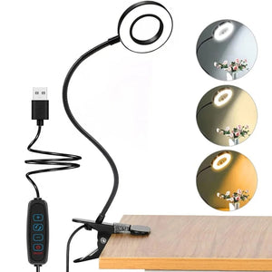 Lampe pince noire avec panneau LED circulaire clipsée sur le bord d'un bureau en bois