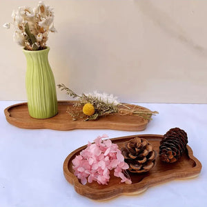Plateau en bois organique avec vase de fleurs séchées et pommes de pin en décoration