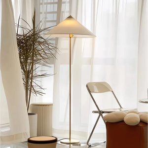 Lampadaire abat-jour tissu crème dans un salon lumineux avec voilages