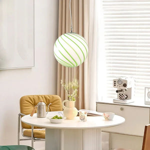 Suspension boule en verre rayée verte au-dessus d'une table
