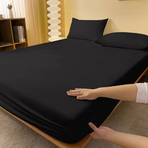 Main posée sur un drap housse noir tendu sur un matelas