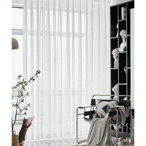 Voilage blanc en tulle transparent couvrant une fenêtre haute dans un intérieur design