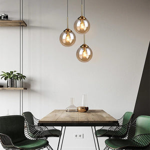3 suspensions globe en verre ambre au-dessus table salle a manger bois ambiance nordique