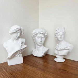 Trois bustes en résine blanche style classique regroupés sur une étagère en bois