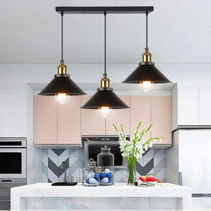 Triple suspension linéaire vintage avec 3 abat-jour noirs au-dessus d'un îlot de cuisine blanc moderne