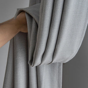 Gros plan sur le tissu texturé gris du rideau formant des plis souples