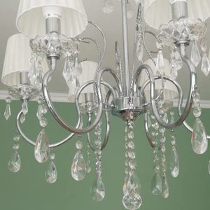 Lustre pampilles avec abat-jours blancs plissés dans salon vert décoration