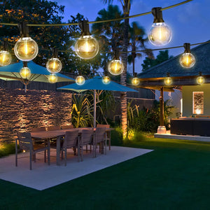 Guirlande lumineuse extérieure guinguette G40 LED installée dans un jardin avec table de repas