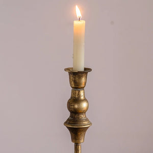 Gros plan sur la bougie allumée et la finition laiton antique du chandelier