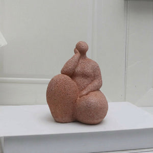 Statuette de femme pensive en résine posée sur un livre blanc