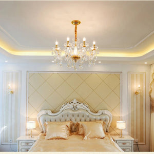 Lustre baroque en cristal doré suspendu au dessus d'un lit capitonné