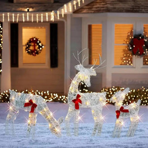 Famille de 3 rennes lumineux devant une maison décorée pour Noël