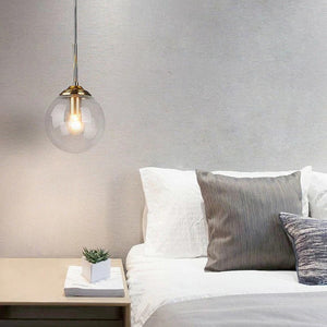 Suspension globe en verre transparent au-dessus chevet chambre nordique minimaliste