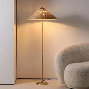 Lampadaire bambou tressé doré allumé lumière chaude près d'un fauteuil