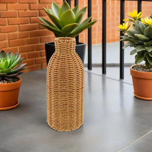 Vase en rotin tressé sur une terrasse en béton devant un mur de briques