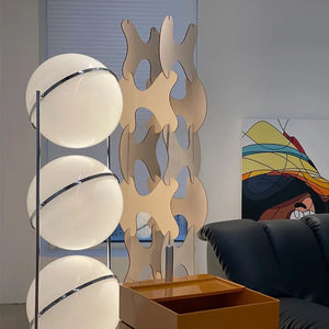 Lampadaire trois boules dans un salon avec bibliothèque en bois