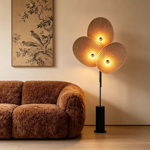 Lampadaire 3 pétales beige allumé dans un salon cosy avec tableau