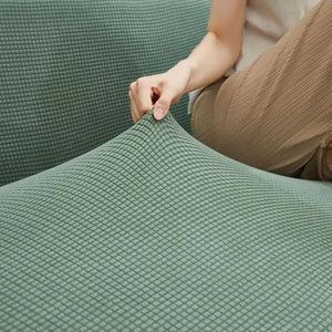 Détail du tissu extensible de la housse de canapé tenu à la main