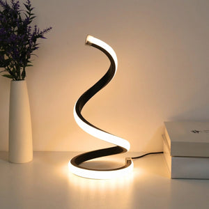 Lampe de bureau LED en spirale allumée posée sur un bureau près d'un vase et de livres