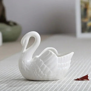 Vase cygne blanc en céramique posé sur une table claire