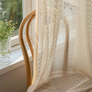 Détail du tissage losange du voilage beige devant une fenêtre avec chaise en bois