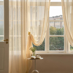 Voilage beige noué embellissant une grande fenêtre dans un salon ensoleillé