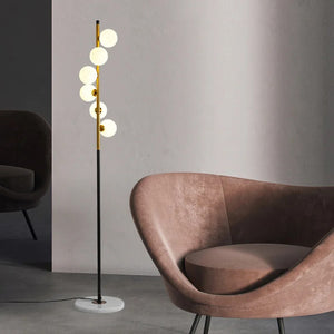 Lampadaire à boules de verre blanc laiteux dans un salon scandinave avec fauteuil rose poudré