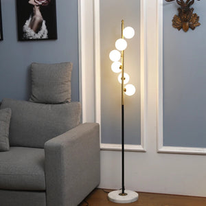 Lampadaire nordique à cinq globes blancs dans un salon lumineux avec canapé gris