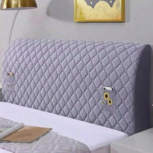 Housse de tête de lit matelassée grise installée sur un lit avec lampe de chevet dorée