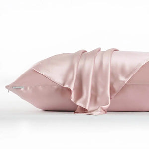Taie d'oreiller en soie rose avec fermeture éclair latérale posée sur un lit