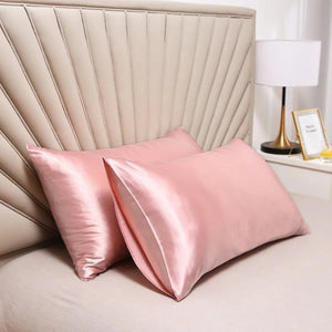 Taies d'oreiller roses en satin disposées sur un lit