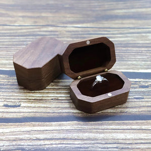 Boîte à bijoux vintage en bois ouverte sur fond bois rustique avec bague solitaire argent