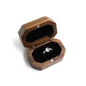 Écrin à bague en bois de noyer octogonal ouvert sur fond blanc avec bague en argent