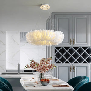 Lustre suspension en plumes blanches au-dessus d'une table à manger avec fleurs